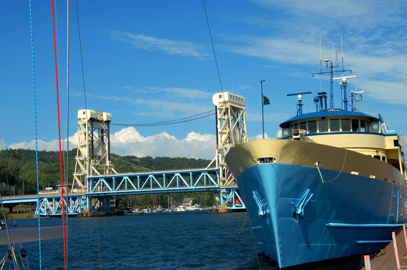 A blue ship in foreground with white and blue iron bridge in background.