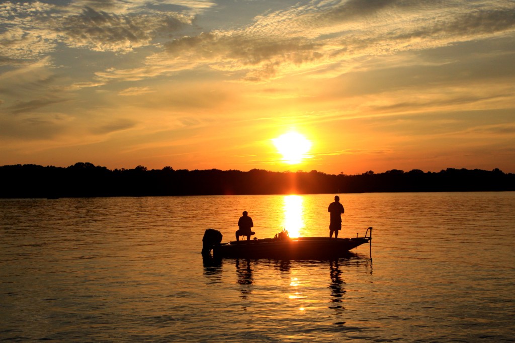 two people fishing at sunset on a quiet lake in Tennessee
