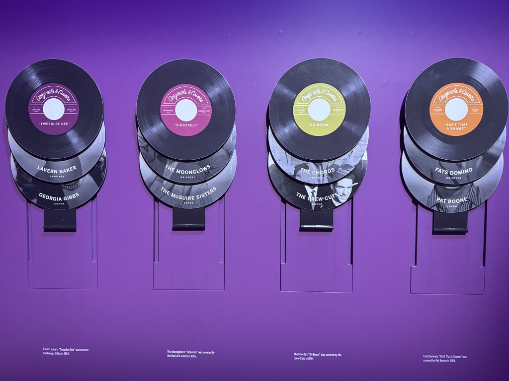an exhibit at the National Museum of African American Music, a deep purple wall with display records hung up layered over each other