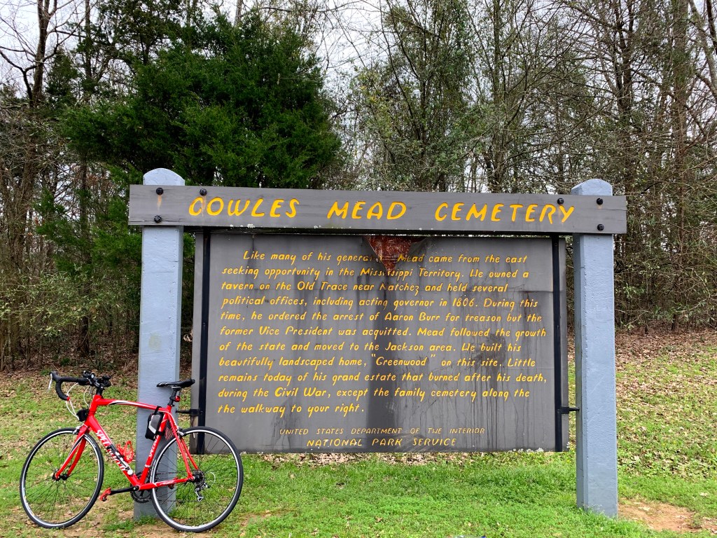 a carved wooden sign with yellow painted letters reading "Cowles Mead Cemetery"